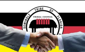A handshake in front of a Seminole Tribe of Florida flag